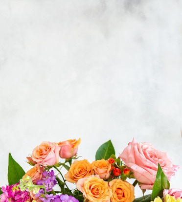 Vibrant arrangement of pink and orange roses complemented by colorful blossoms, ideal for gifts.