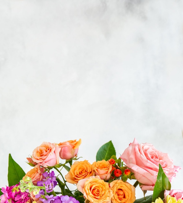Vibrant arrangement of pink and orange roses complemented by colorful blossoms, ideal for gifts.