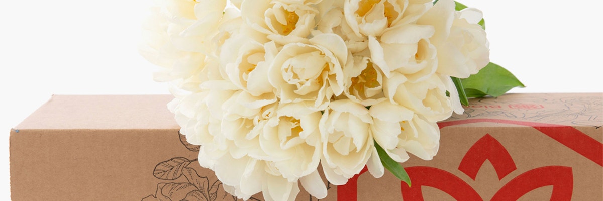 Elegant bouquet of white tulips resting on a decorative gift box, ideal for celebrations and gifts.