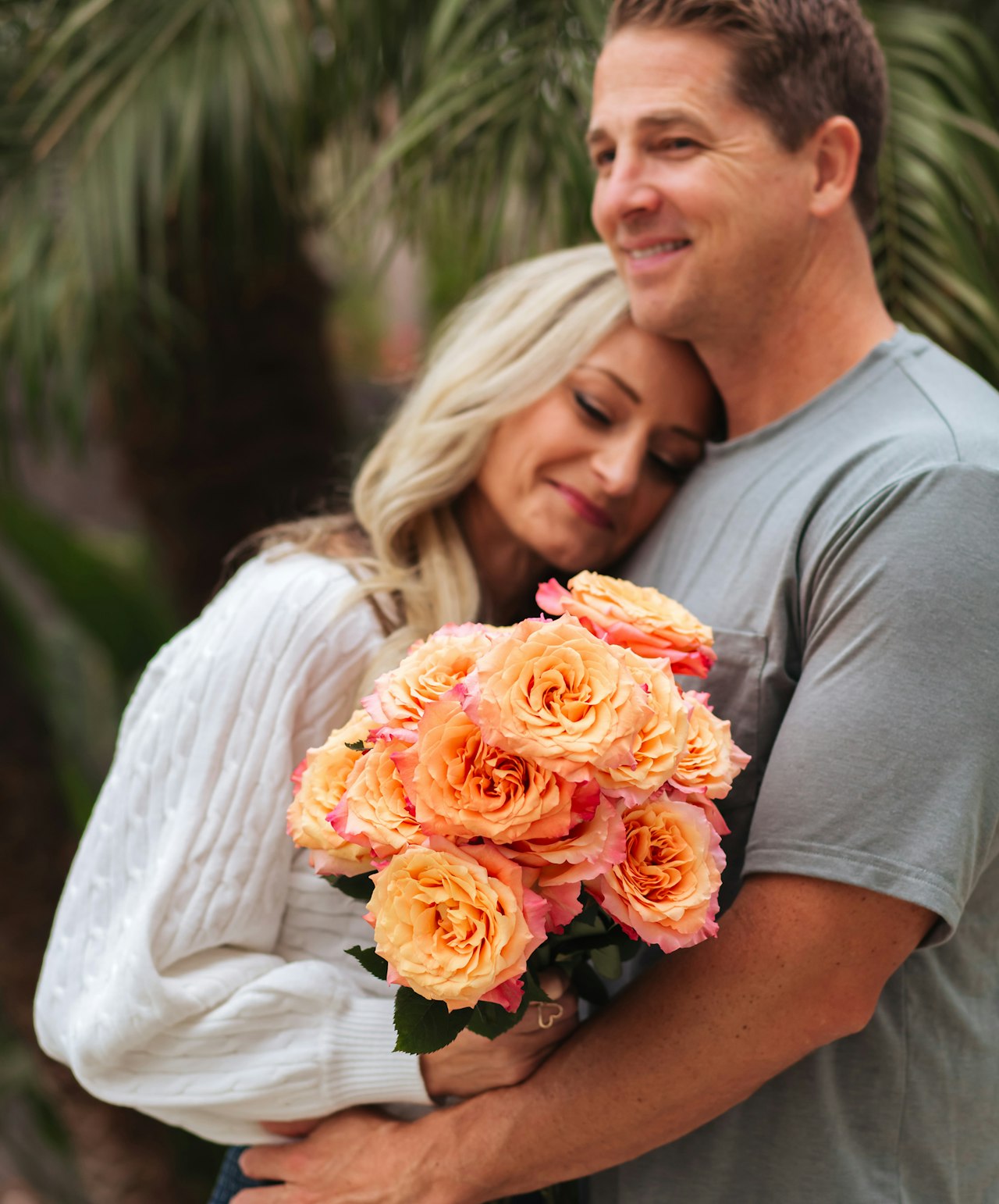 A man and woman holding an orange bouquet that was recieved as a special occassion gift.