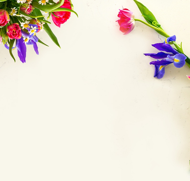Vibrant floral arrangement featuring colorful tulips, daisies, and irises on a light background.