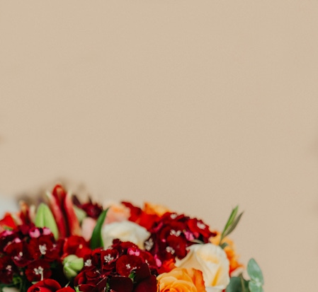 Vibrant floral arrangement featuring red, orange, and white blooms against a soft background.