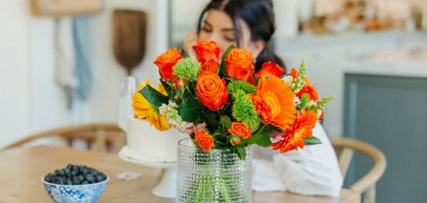 Vibrant bouquet of orange roses and cheerful daisies brightening a cozy kitchen table.