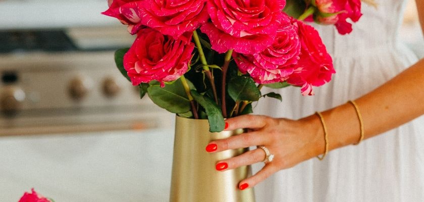 Vibrant pink roses elegantly arranged in a sleek gold vase, bringing cheer to any space.