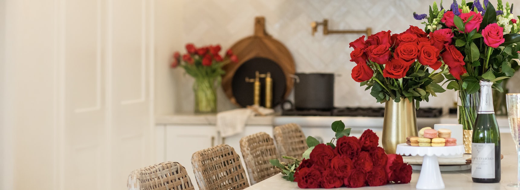 Elegant kitchen setting featuring vibrant red roses and charming macarons on display.