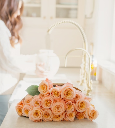 A fresh bouquet of pale orange roses arranged elegantly on a kitchen countertop.