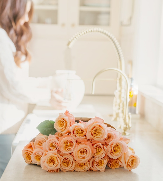 A fresh bouquet of pale orange roses arranged elegantly on a kitchen countertop.