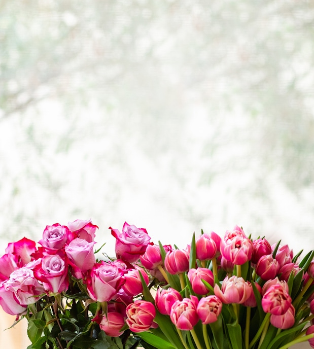 Elegant arrangement of pink roses and tulips with a soft blurred background.
