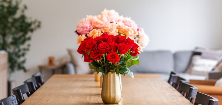 Vibrant floral arrangement featuring red roses and pastel peonies in a modern vase.