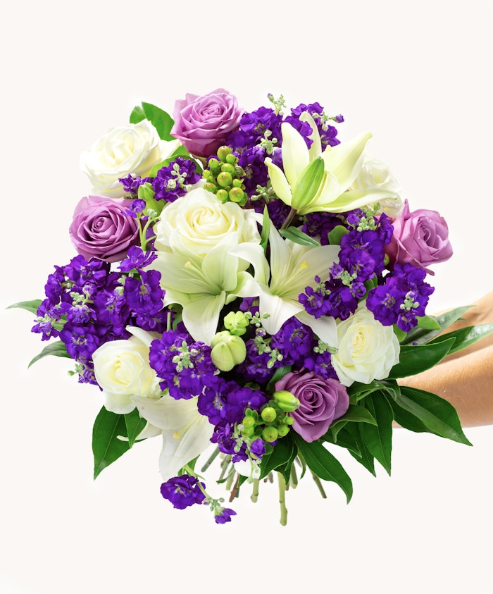Vibrant floral bouquet featuring white lilies, purple and lavender roses, and lush greenery.