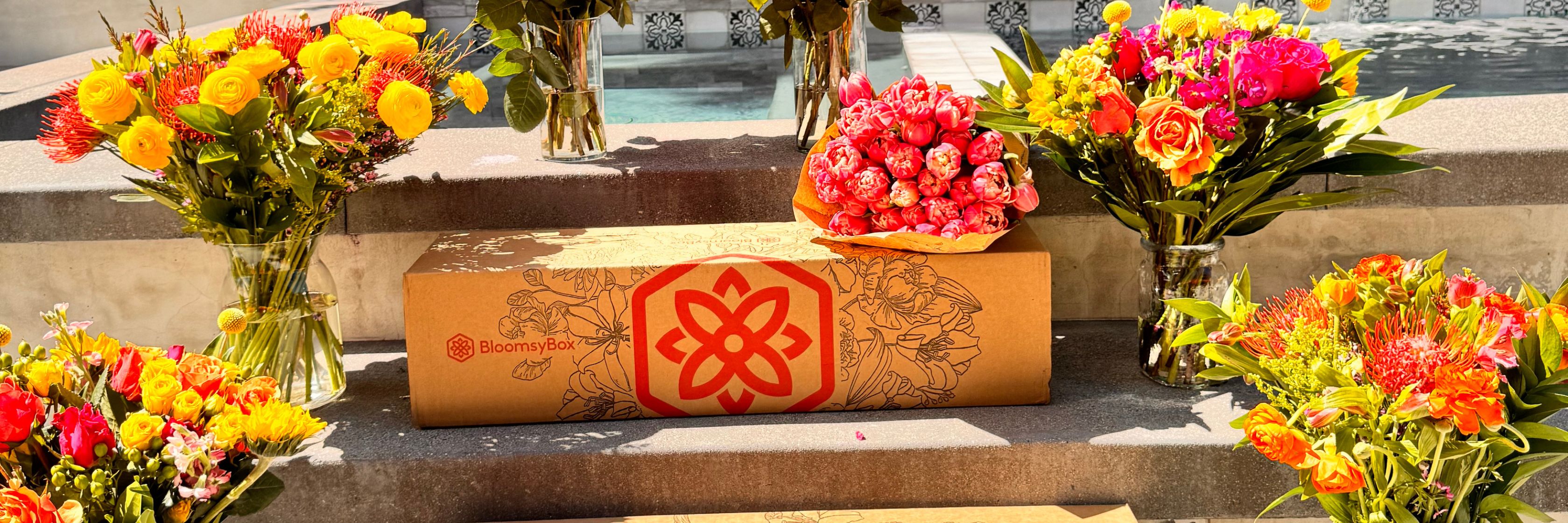 Vibrant floral arrangements in various colors surrounding a BloomsyBox package, perfect for gifting.