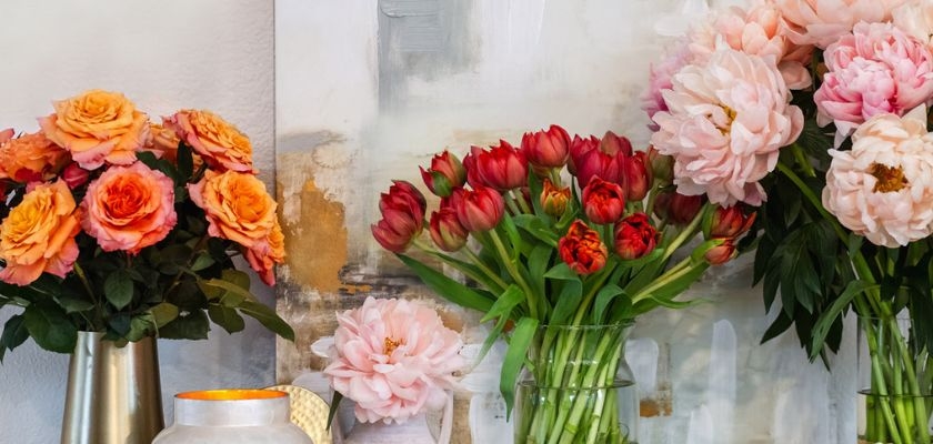 Vibrant floral arrangement featuring peach roses and red tulips in elegant vases.