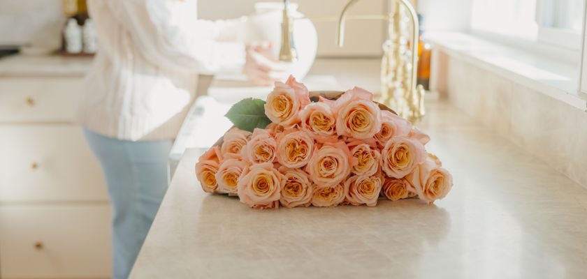 A vibrant arrangement of soft peach roses on a kitchen countertop, enhancing a cozy atmosphere.
