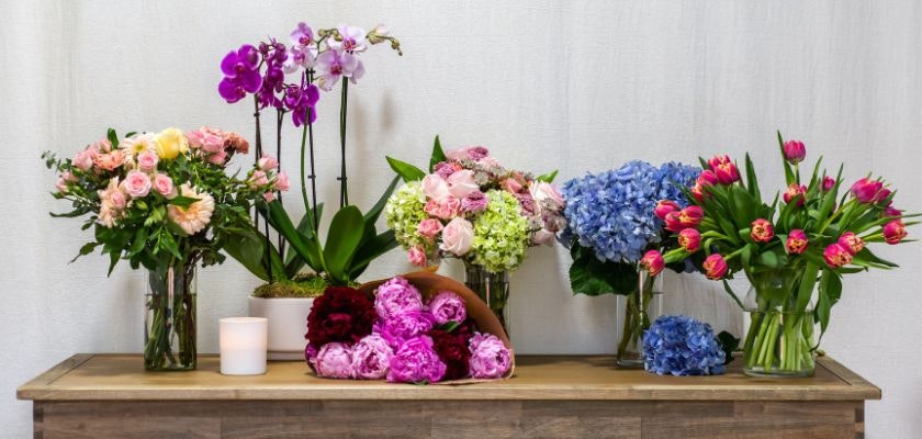 Vibrant flower arrangement display featuring roses, tulips, peonies, and orchids in elegant vases.