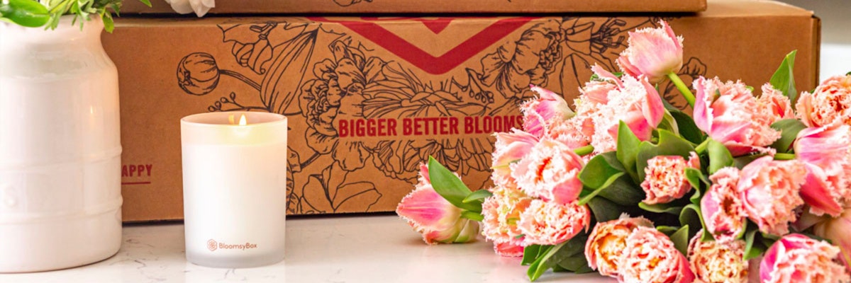 Elegant pink tulips next to a candle and a subscription box, perfect for floral delivery lovers.