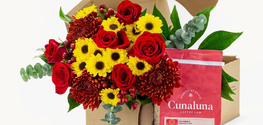 Vibrant floral bouquet featuring red roses, yellow sunflowers, and rich foliage, paired with coffee.