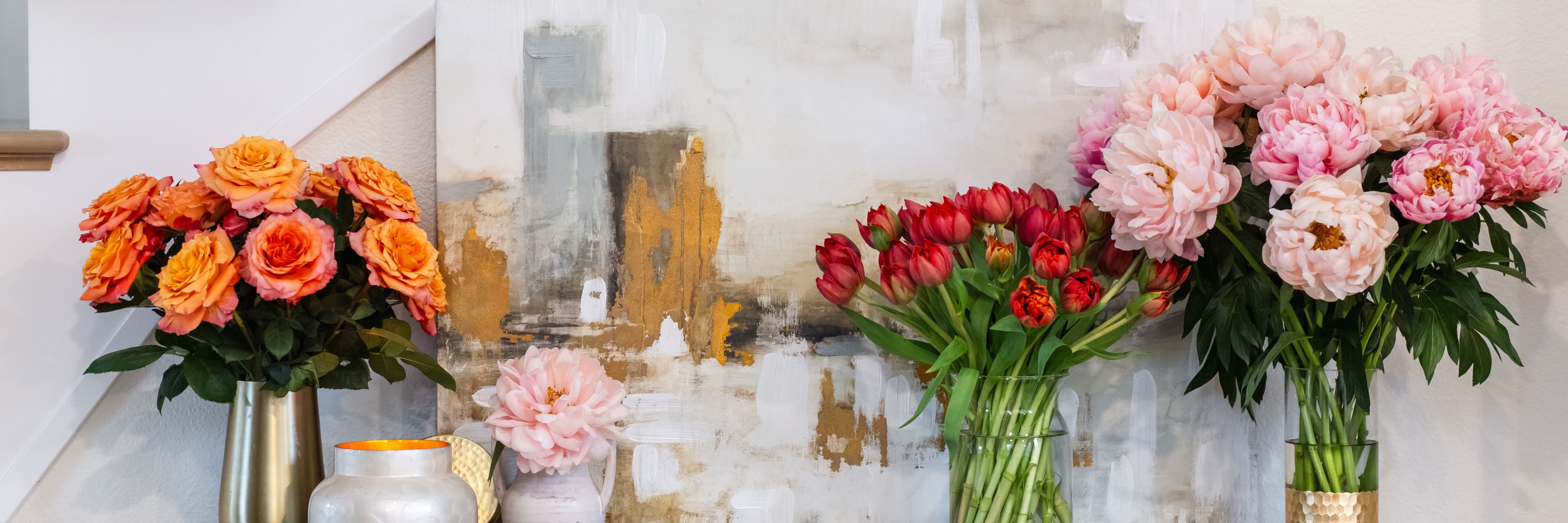 Elegant floral arrangement featuring vibrant roses and peonies near modern art decor.