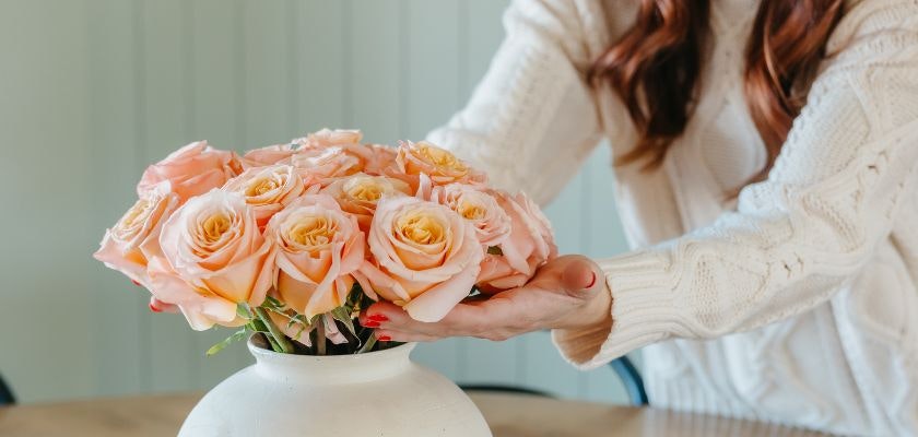 A soft bouquet of pink and yellow roses elegantly displayed in a stylish white vase.