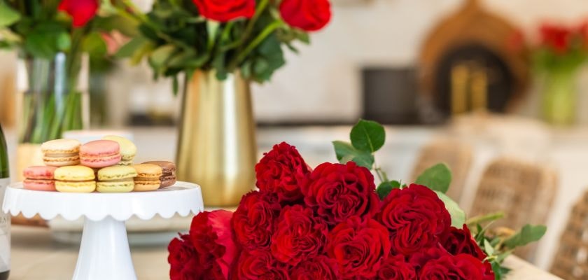 A vibrant display of red roses with macarons, adding elegance to a stylish table setting.