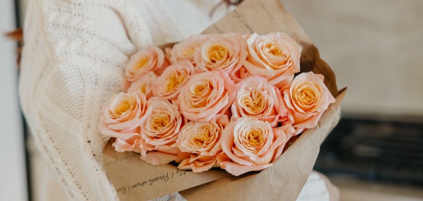 A beautiful arrangement of peach roses wrapped in elegant brown paper, perfect for any occasion.