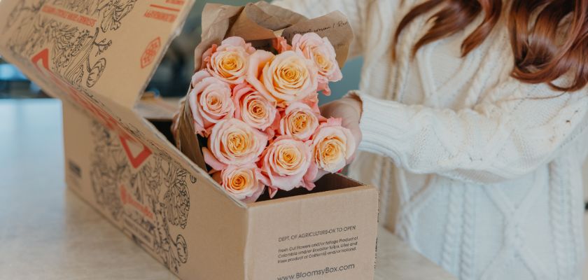 A beautiful arrangement of peach roses being unpacked from a BloomsyBox delivery.