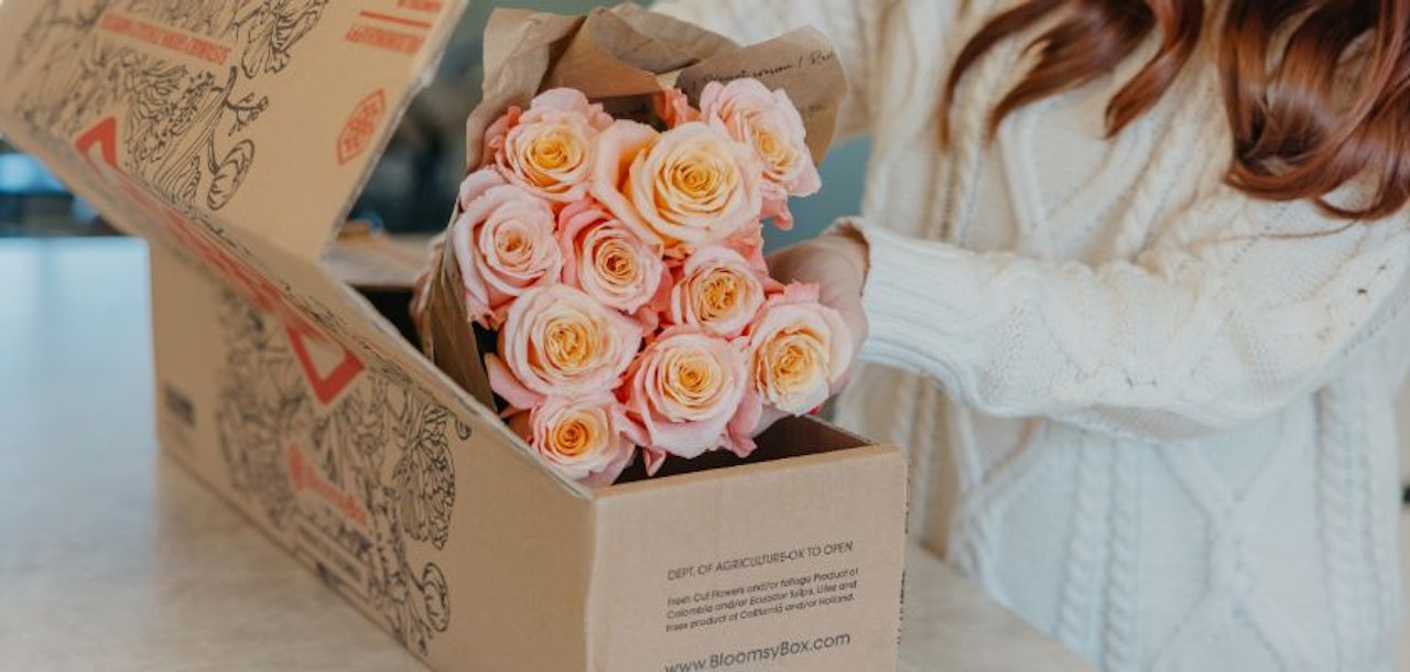 Beautiful peach roses being unwrapped from a BloomsyBox delivery, showcasing their fresh petals and vibrant colors.