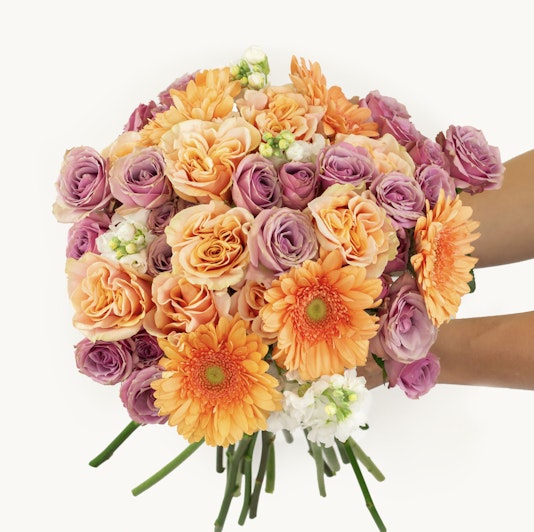 Vibrant bouquet featuring orange gerbera daisies, pink and peach roses, perfect for any celebration.