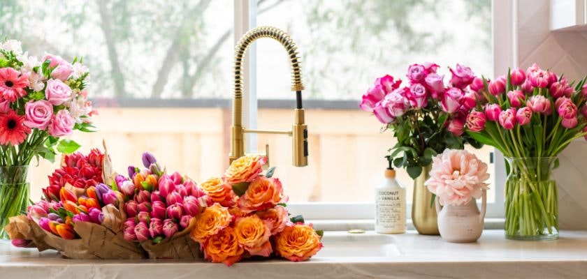 Vibrant floral display featuring an assortment of roses and tulips by a sunny window.