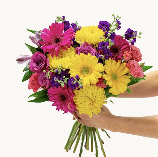 Vibrant bouquet featuring pink gerbera daisies, yellow chrysanthemums, and purple blooms.