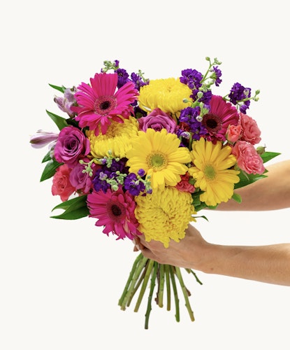 Vibrant bouquet featuring pink gerbera daisies, yellow chrysanthemums, and purple blooms.