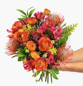 Vibrant bouquet featuring orange ranunculus, protea, and pink alstroemeria blooms.