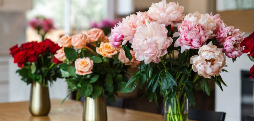 Elegant floral arrangement featuring lush pink peonies and vibrant red roses in stylish vases.