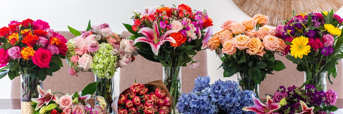 Colorful floral arrangements featuring roses, lilies, and various blooms in elegant vases.