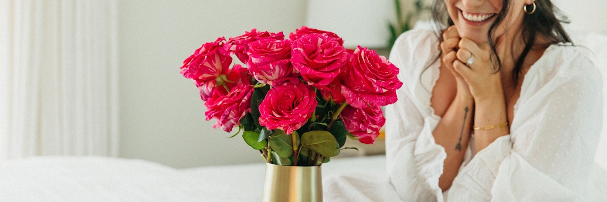 Vibrant pink roses in a gold vase, enhancing a cozy bedroom setting with natural beauty.