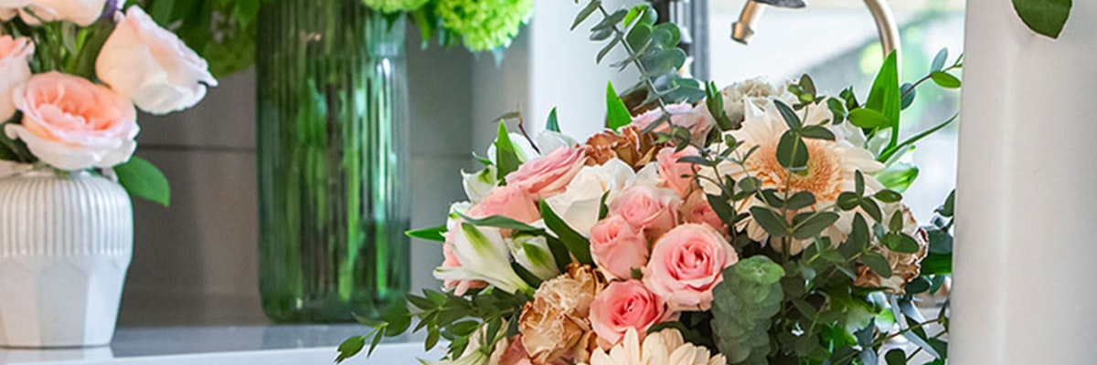 A lush floral arrangement featuring pink roses, white daisies, and greenery for elegant occasions.