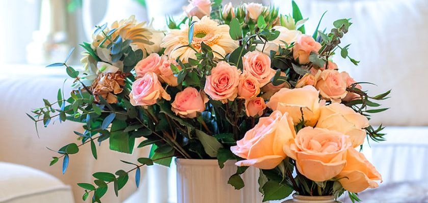 Charming floral arrangement featuring soft pink and peach roses with lush greenery, ideal for decor.