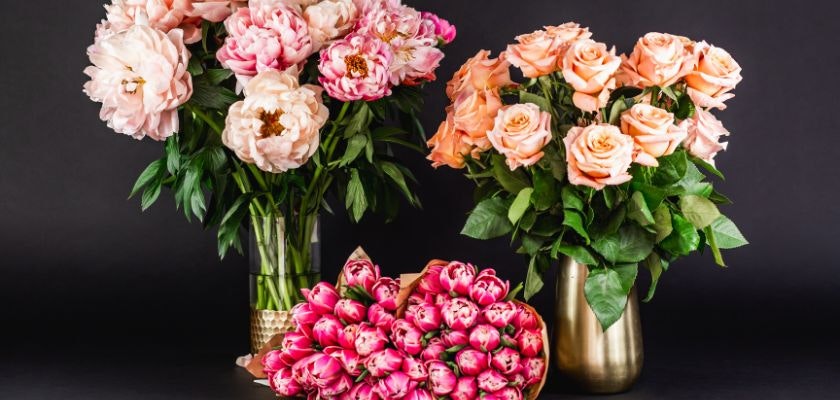 Vibrant floral arrangement featuring pink peonies and peach roses in elegant vases.