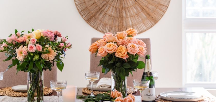 Elegant floral arrangements of peach and pink roses on a dining table.