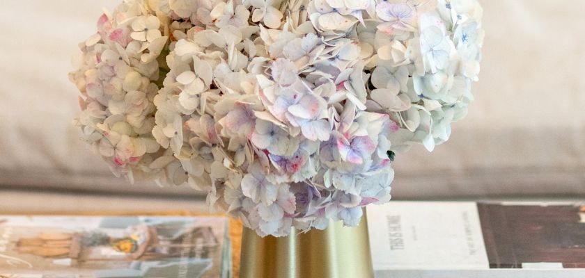 Elegant white hydrangea bouquet in a gold vase, perfect for home décor or special events.