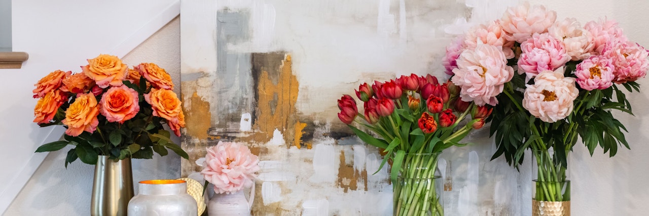 Vibrant floral arrangement featuring roses, peonies, and tulips in elegant vases.