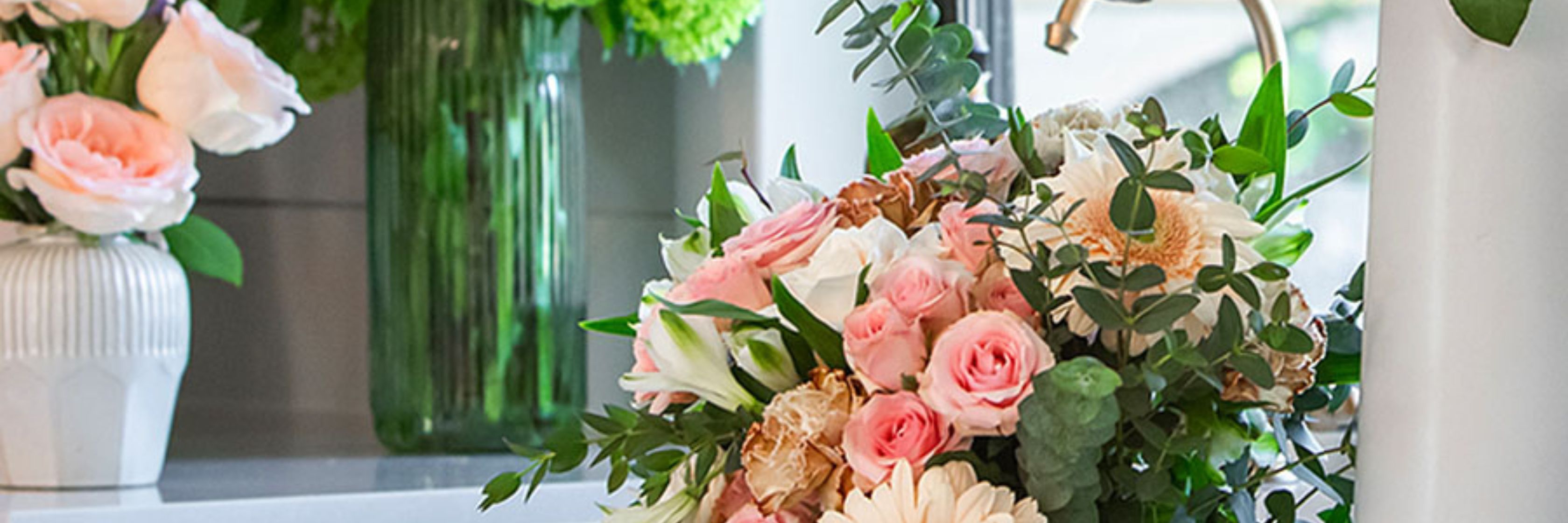 Delicate floral arrangement featuring pink roses, white daisies, and lush greenery.