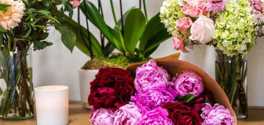 Beautifully arranged peonies in shades of pink and burgundy, surrounded by fresh flowers.