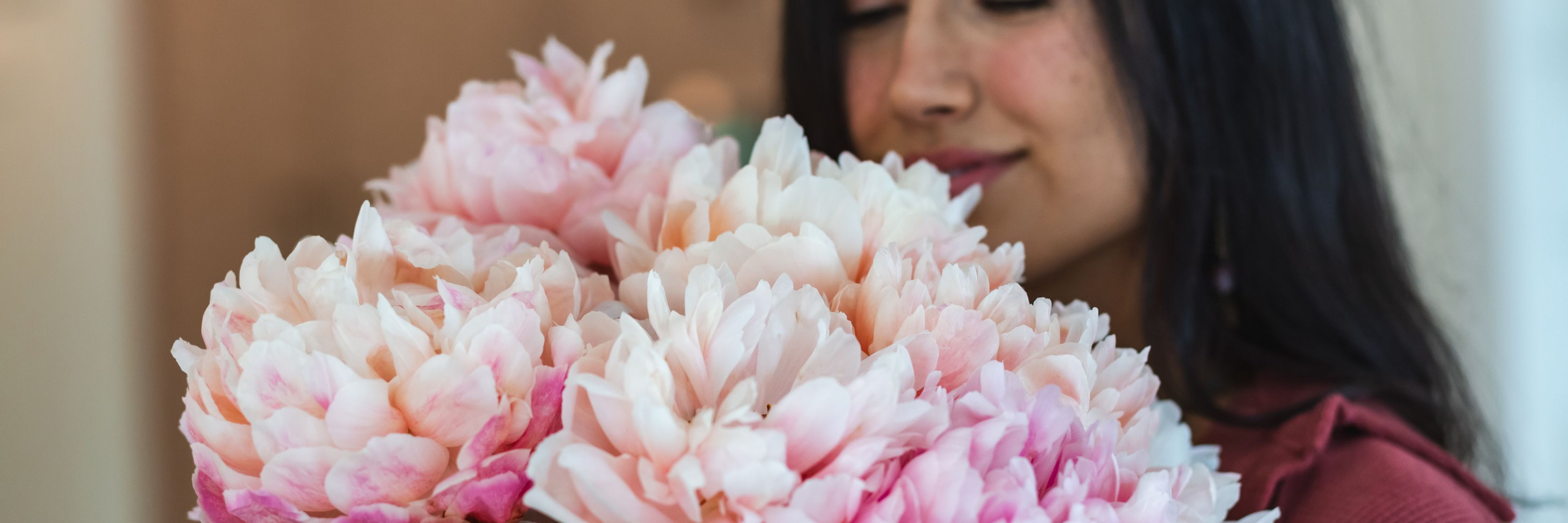 A woman admiring a large bouquet of soft pink peonies in a beautiful floral display.