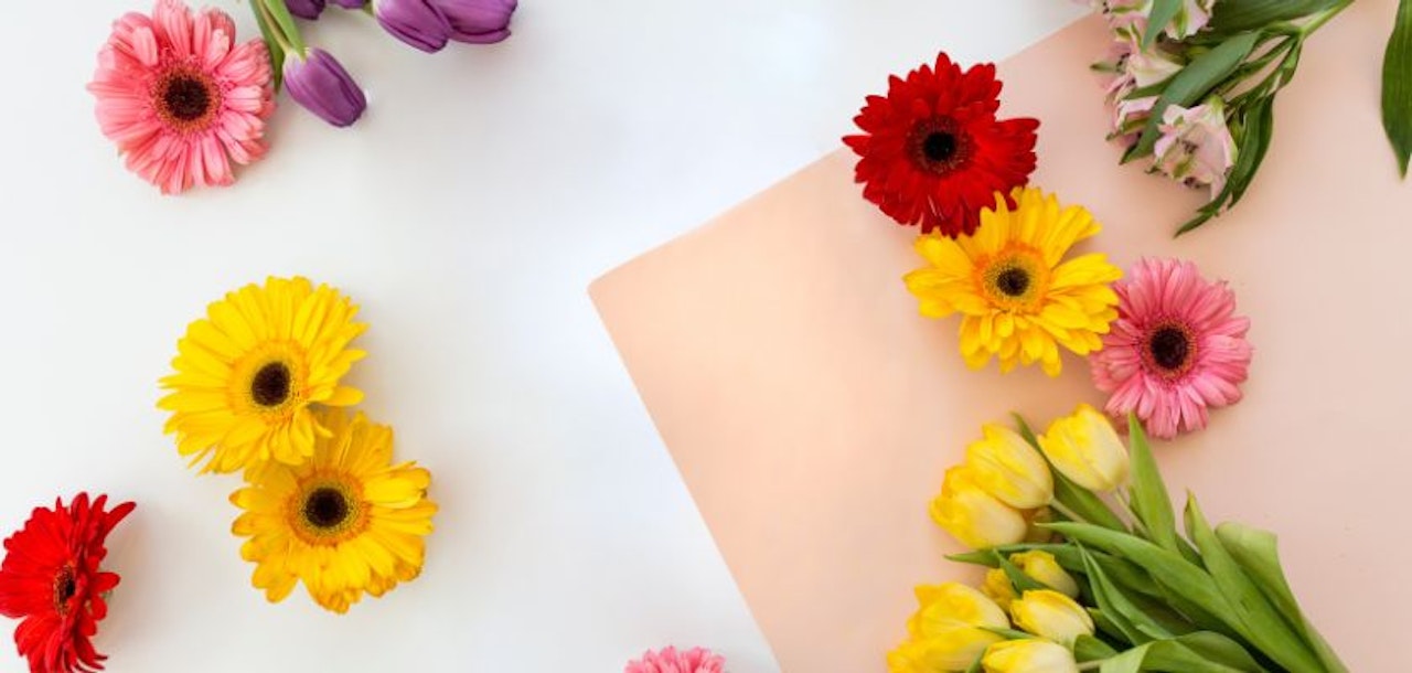 Colorful floral arrangement featuring yellow gerberas, tulips, and vibrant pink blooms.