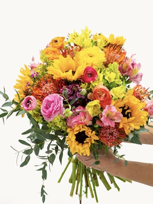 Vibrant bouquet featuring sunflowers, ranunculus, and colorful blooms, perfect for celebrations.