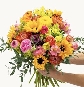 Vibrant bouquet featuring sunflowers, ranunculus, and colorful blooms, perfect for celebrations.