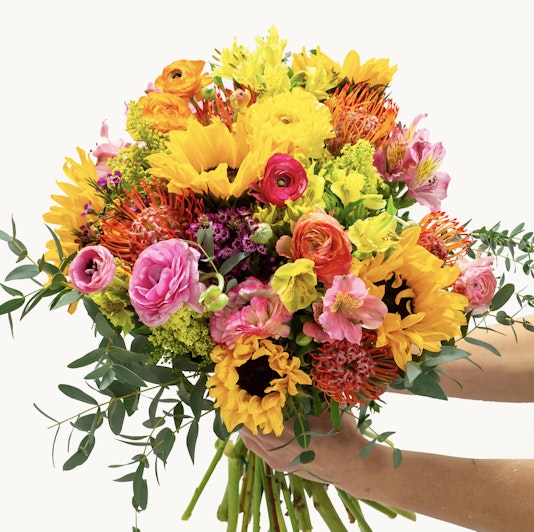 Vibrant bouquet featuring sunflowers, ranunculus, and colorful blooms, perfect for celebrations.