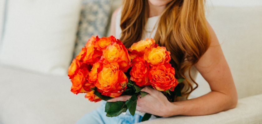 Bright orange and yellow roses held by a woman, creating a vibrant floral display.