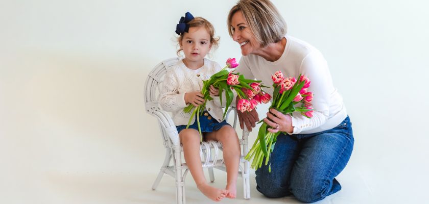 A joyful scene of a woman and a girl holding tulips, captured in a cozy studio setting.