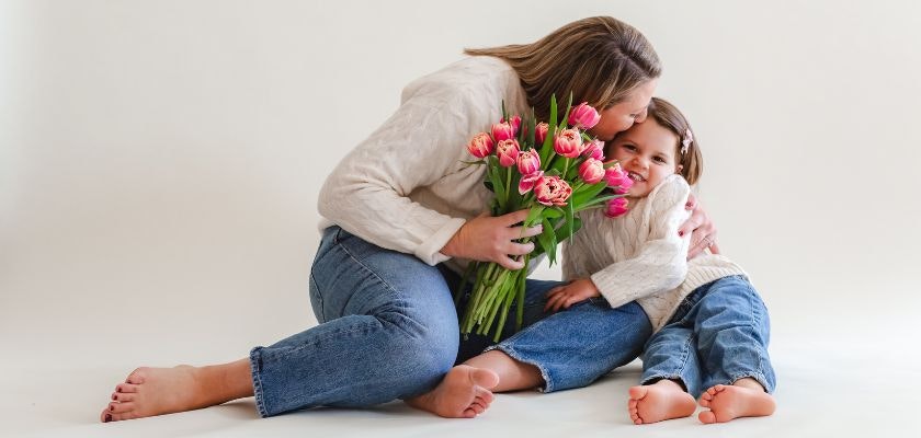 A joyful mother and daughter celebrate together with a vibrant bouquet of pink tulips.